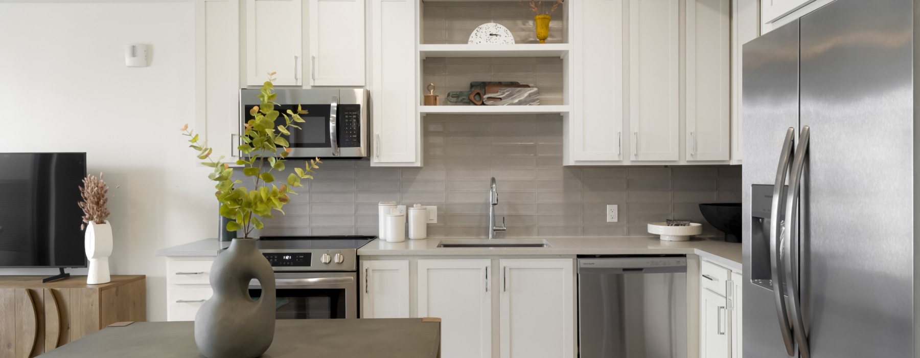 Skyline one bedroom apartment kitchen with stainless steel appliances, white cabinets, open shelving, and contemporary design