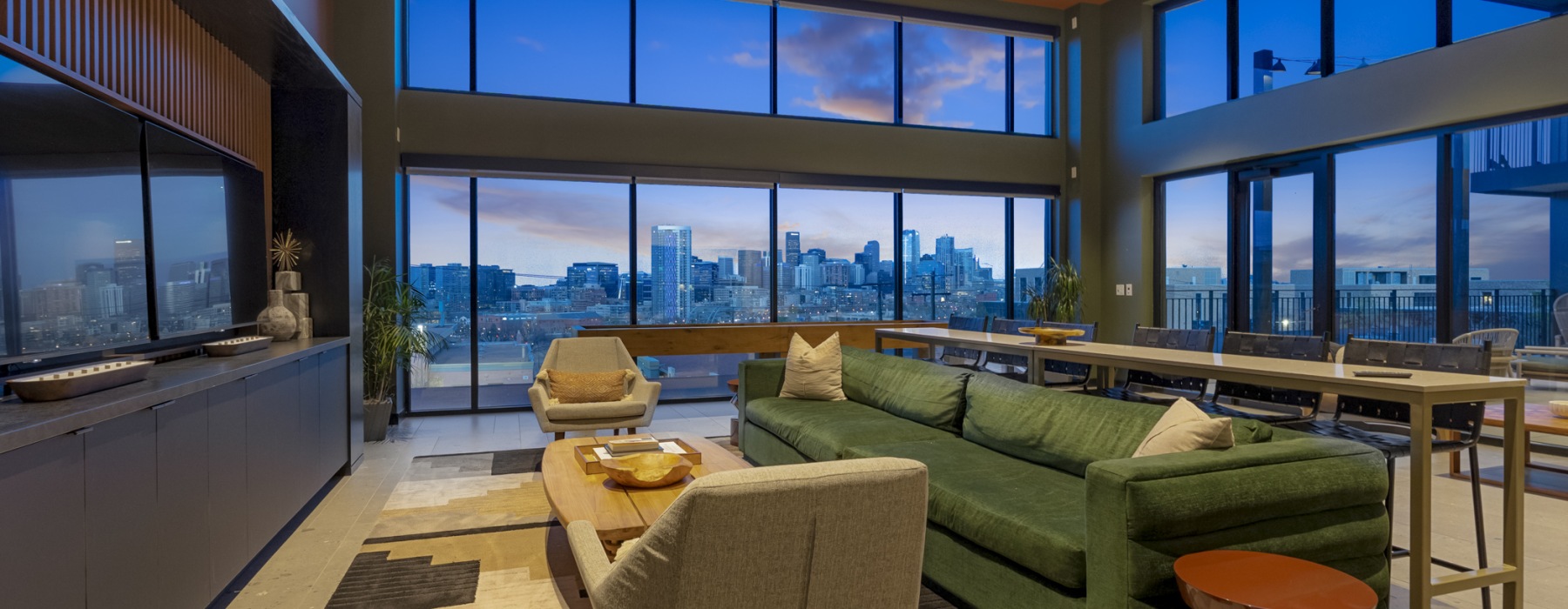 Modern resident lounge at Skyline at Highlands with floor-to-ceiling windows, Denver skyline views, contemporary seating, and shared dining space